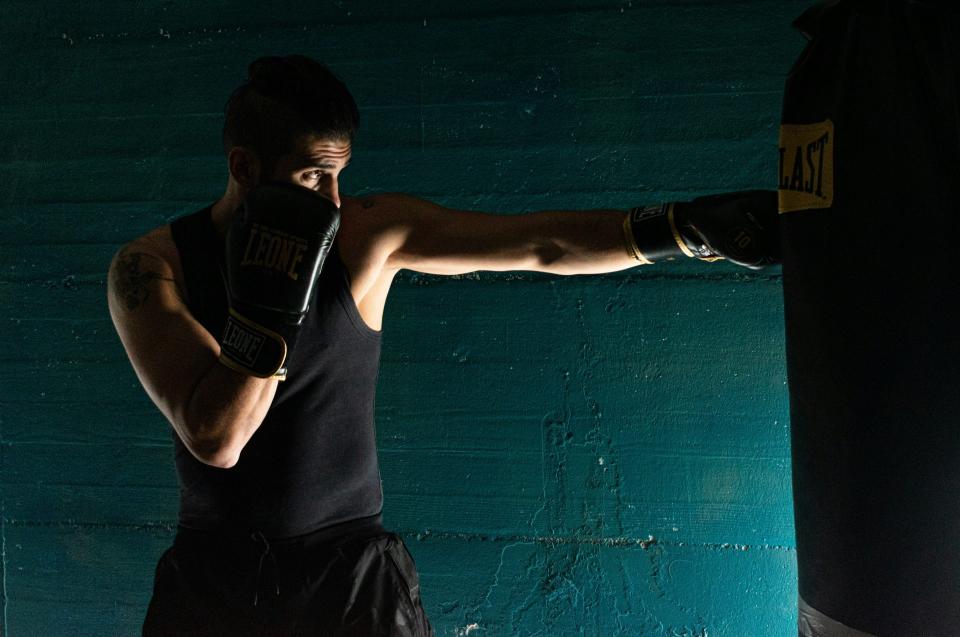 Hombre con camiseta negra sin mangas y pantalones cortos negros con guantes de boxeo negros