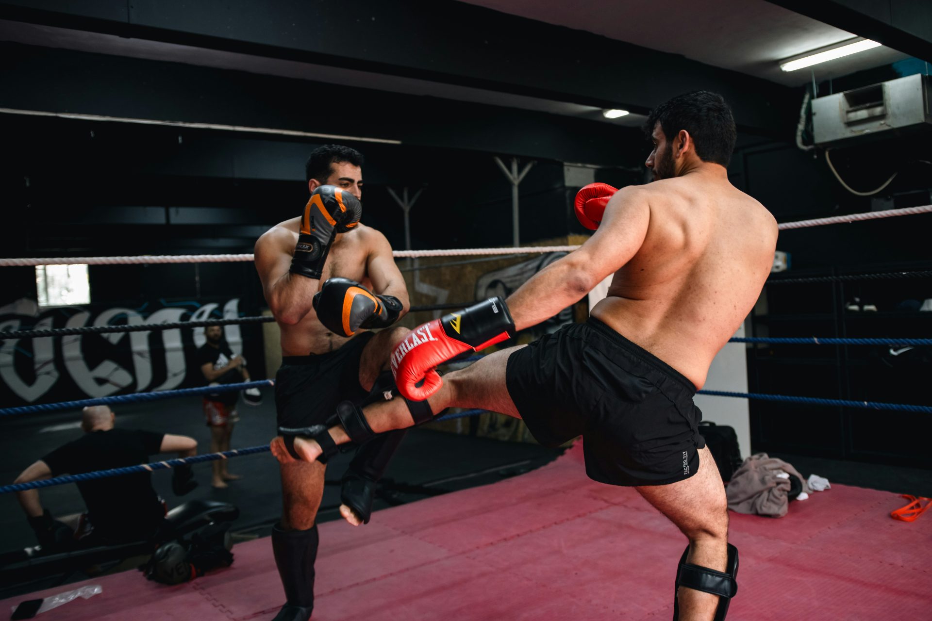 Un hombre pateando a otro hombre en un ring de boxeo.